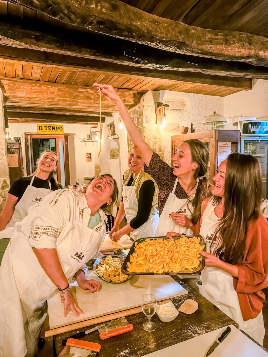 Mate group laughing while making fresh pasta together in a cooking class